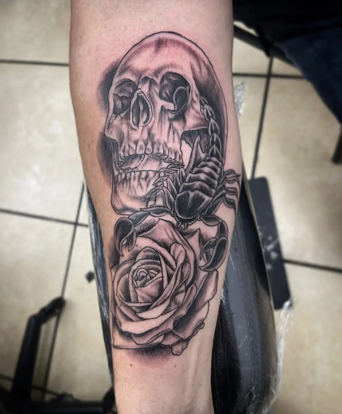 A black and white tattoo of a skull with roses