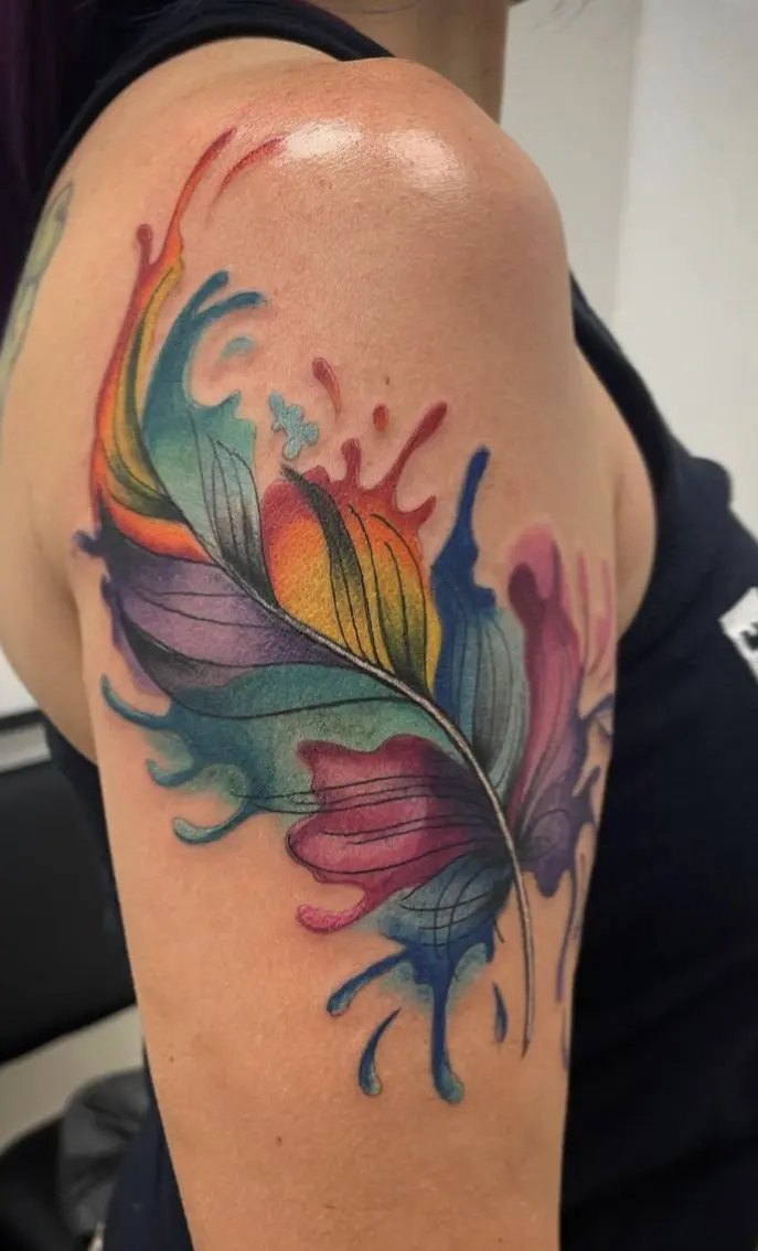 A colorful feather tattoo on the arm of a woman.