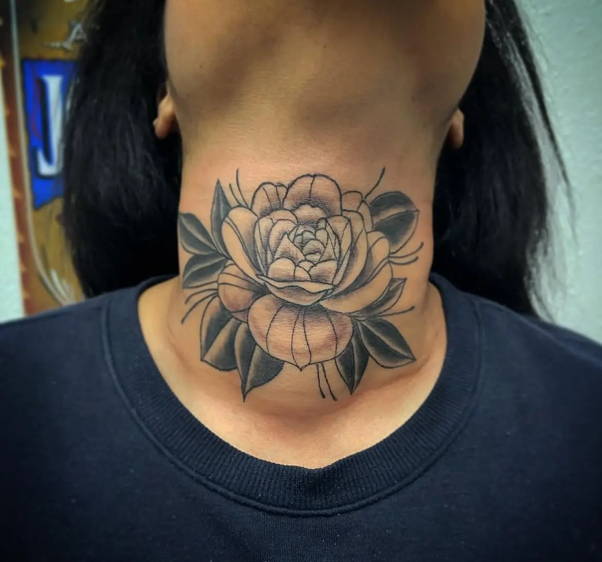 A woman with a flower tattoo on her neck.