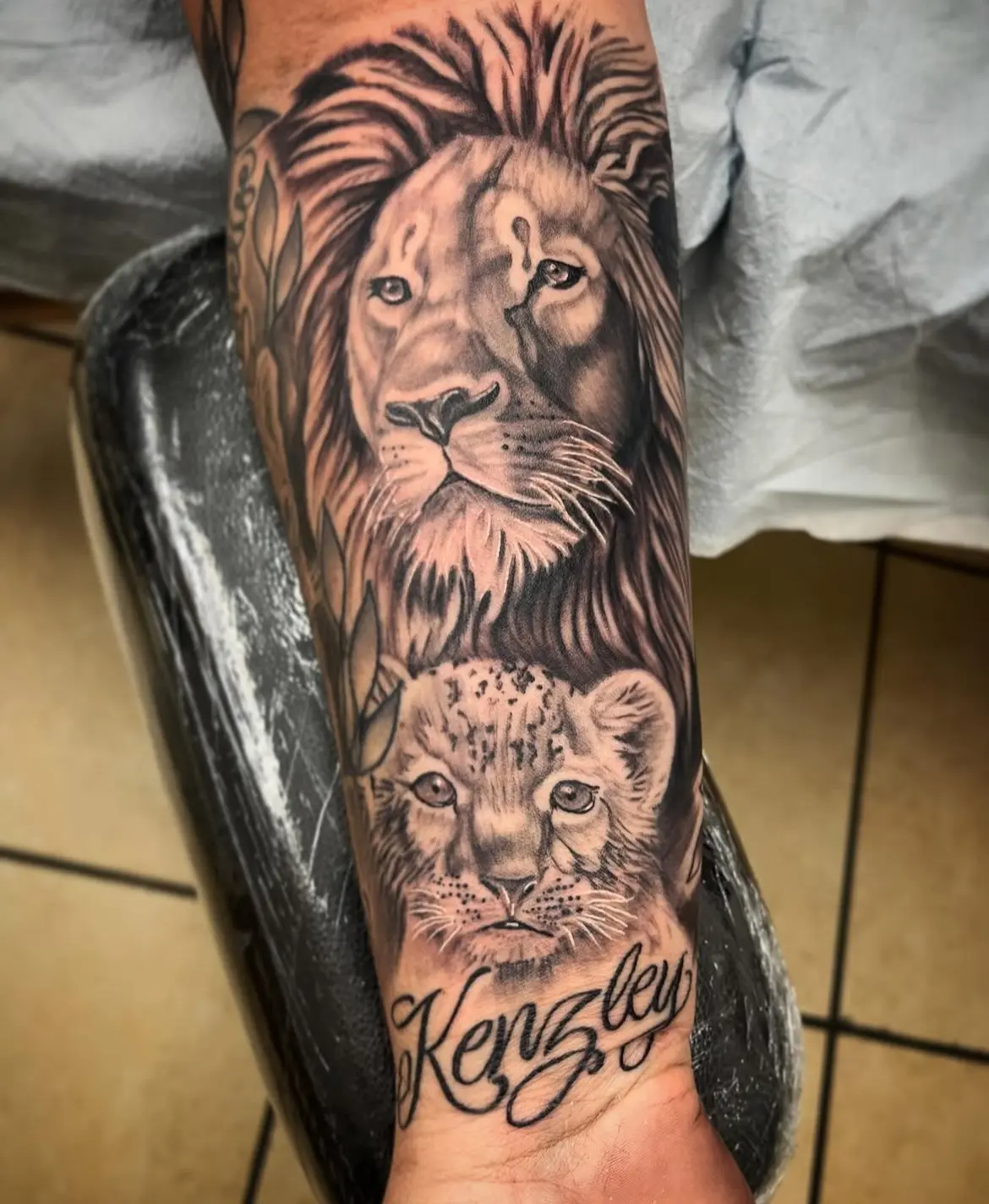 A tattoo of two lions with the name kingsley on it.