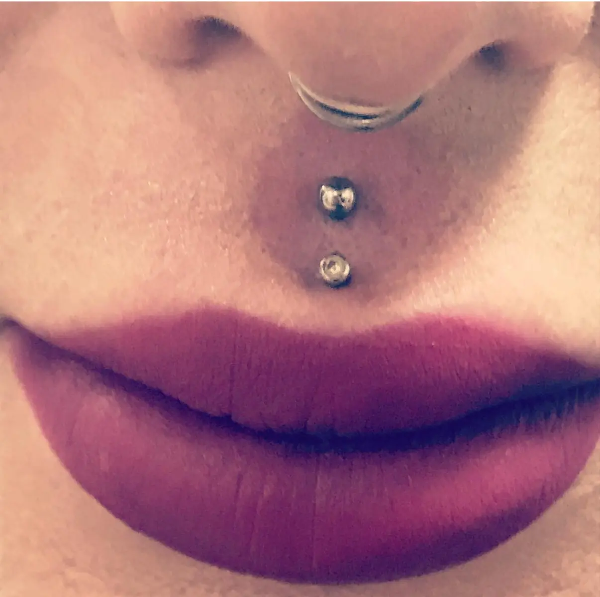 A woman with her lips and nose piercing.