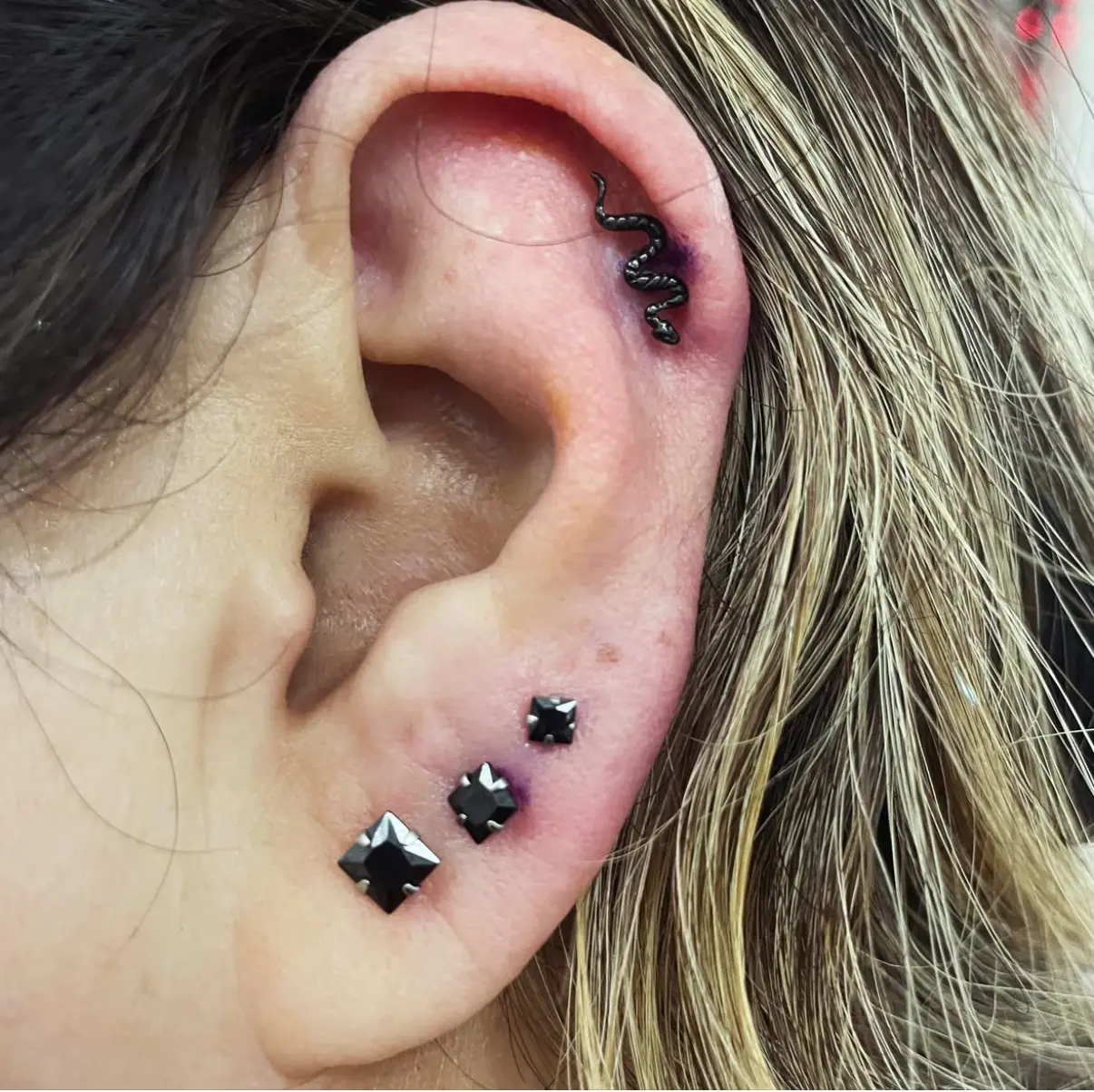 A woman with multiple piercings on her ear.