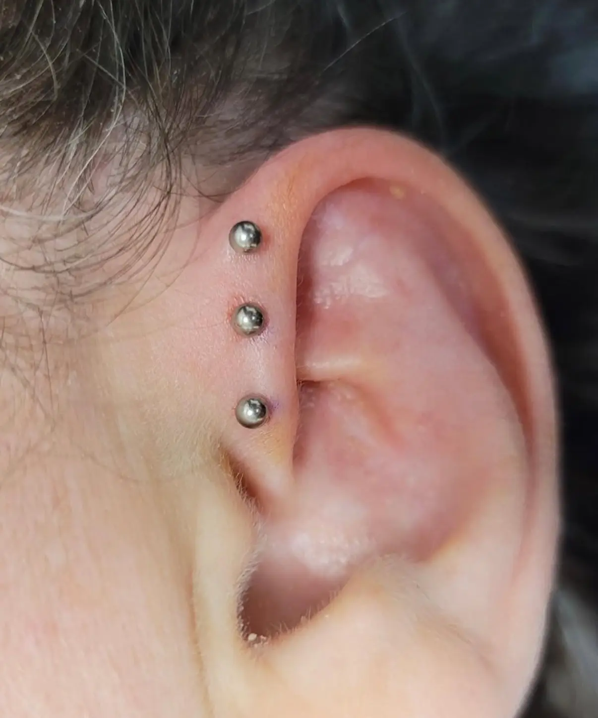 A person with their ear piercings in the ear.