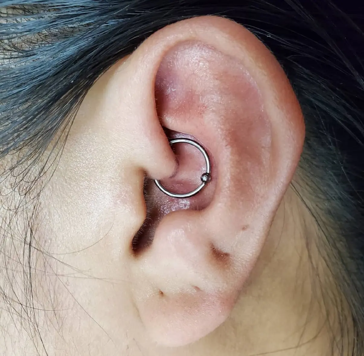 A woman with her ear piercing in the shape of an arrow.