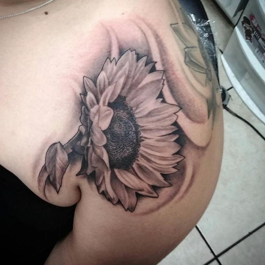 A tattoo of a sunflower on the shoulder.